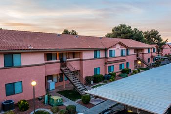 A pink building with a metal roof and a parking area in front.